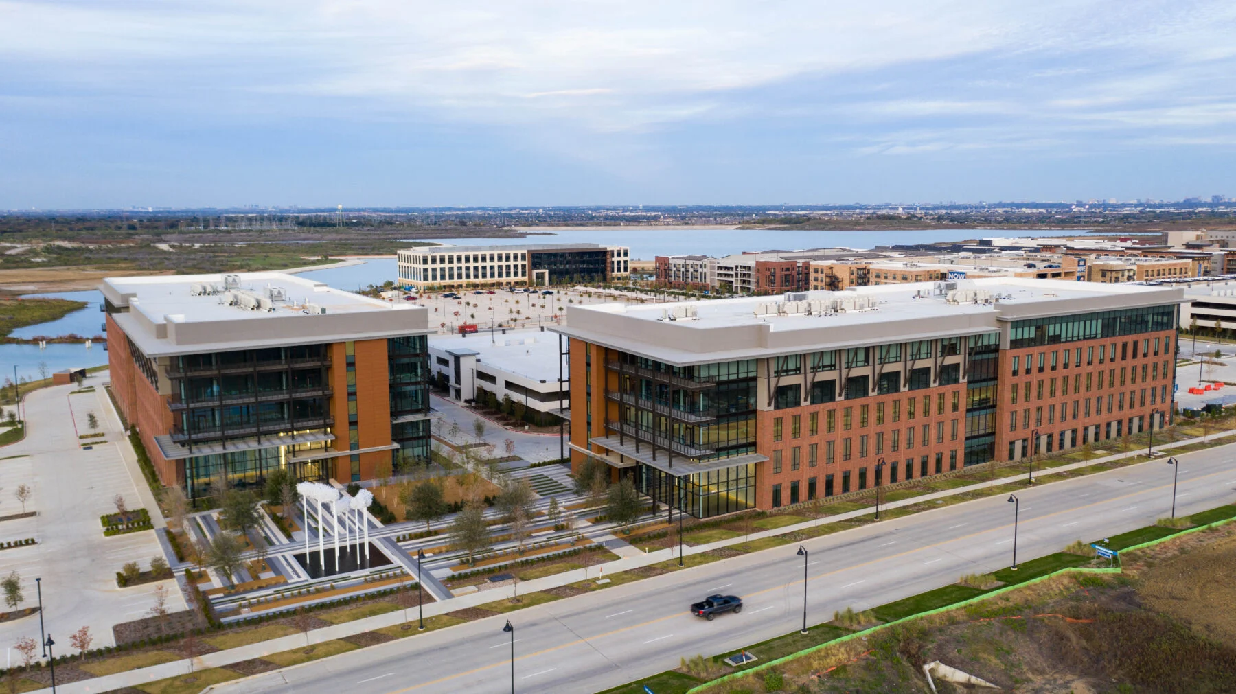 drone view of two five story buildings with fountain and lake