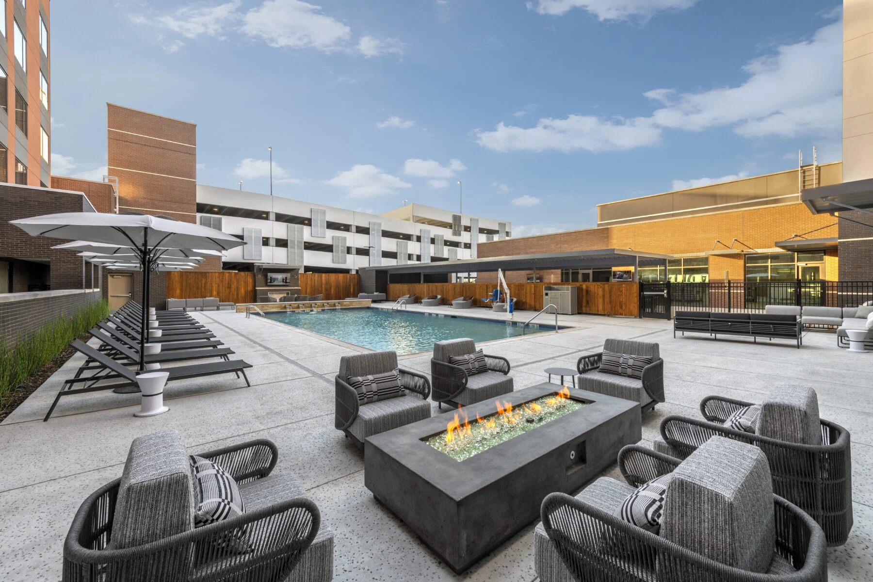 Hotel pool and patio with lounge chairs and fire pit.
