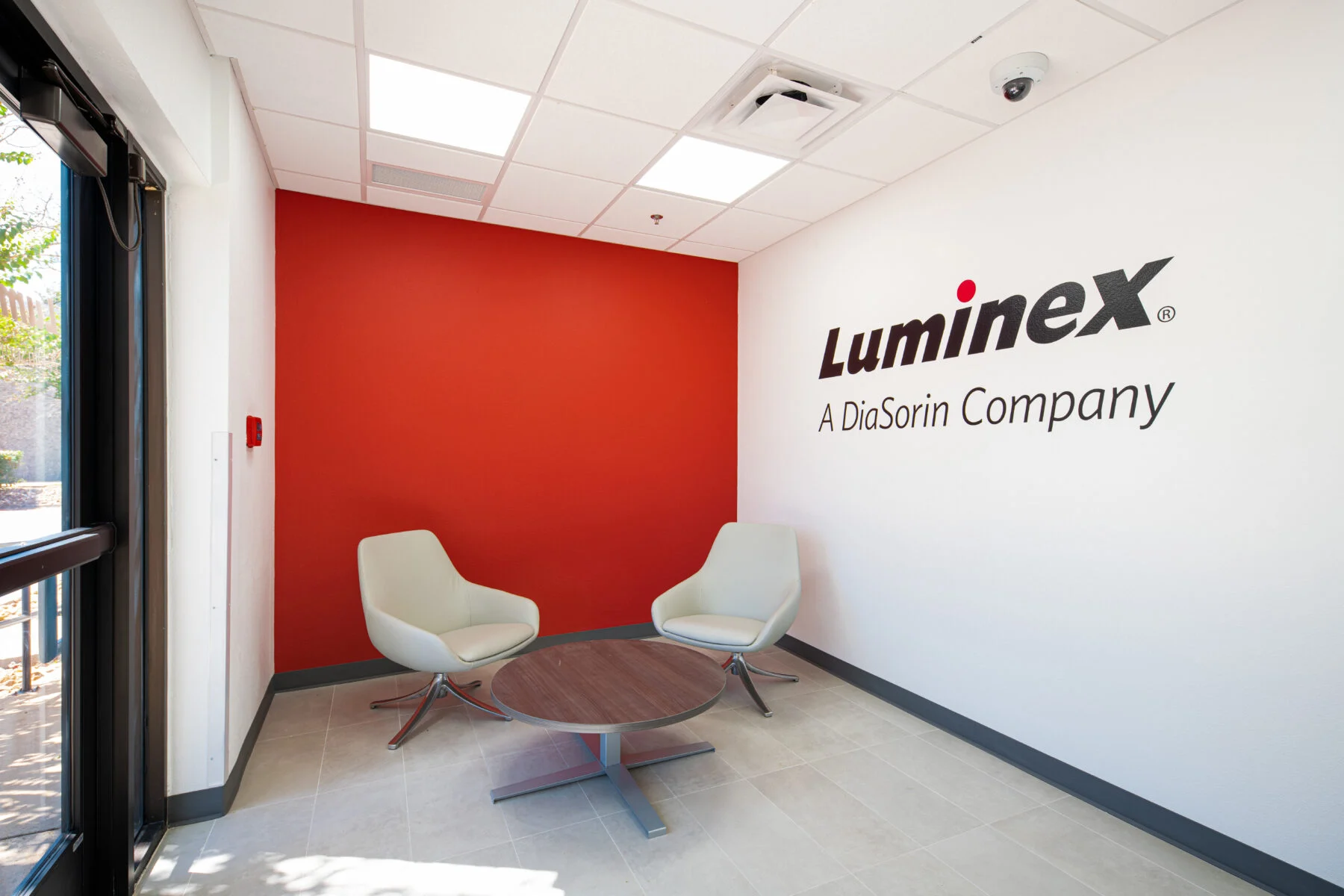 entry lobby of luminex with two white chairs and red wall