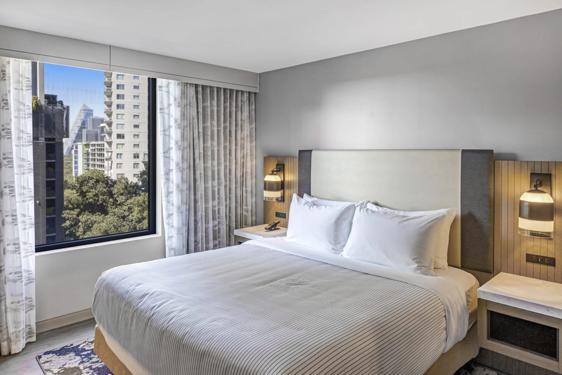 King Bed hotel room with windows overlooking downtown austin.