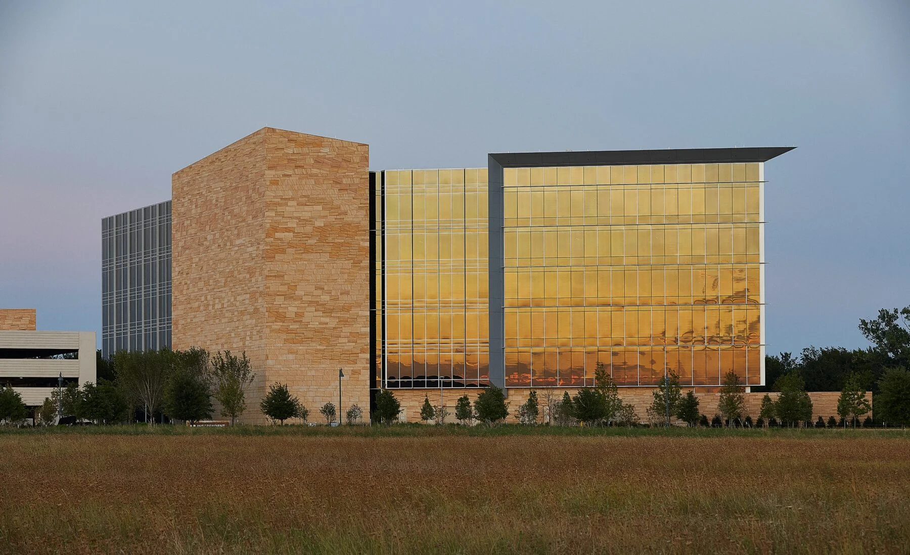exterior of 6 story office building with stone accent wall at sunset