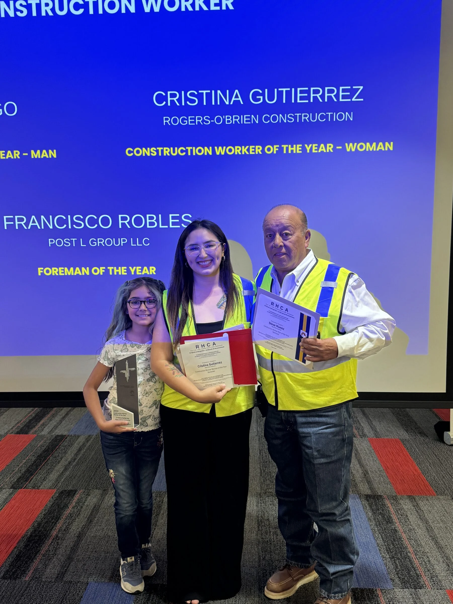 woman accepting construction award with co worker and child